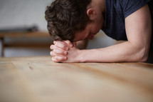 a man with his head on praying hands 