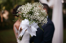 Photograph of a bride and groom kissing behind a bouquet after wedding ceremony.