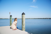 a woman sitting on a pier 