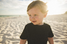 toddler boy standing on a beach 