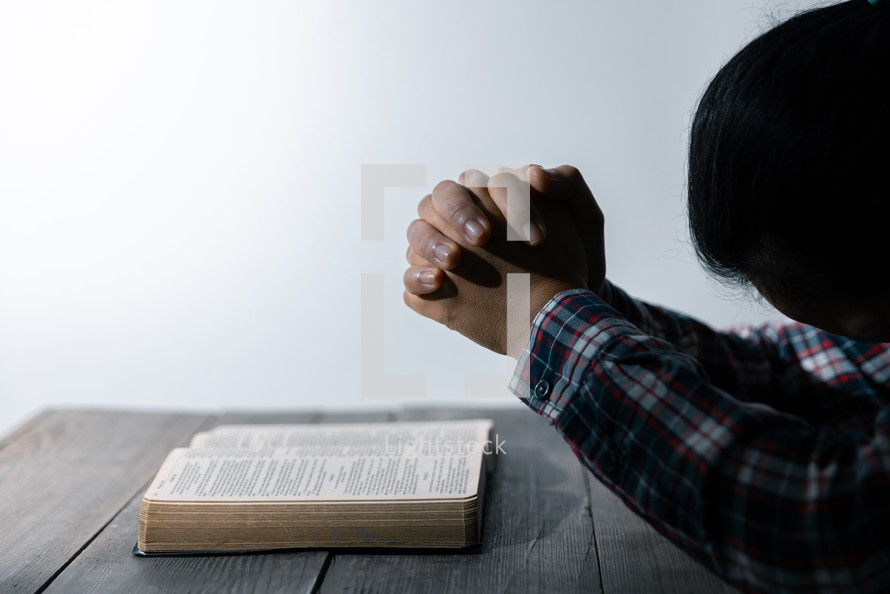 White background and woman praying over Bible