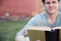 man reading a book outdoors 