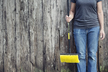 woman holding a push broom in front of a fence 