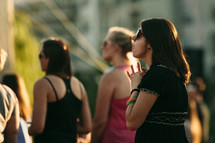 woman holding her hands in prayer at an outdoor worship service 
