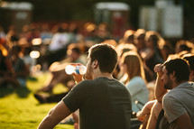 people sitting in the grass at an outdoor christian music concert 