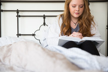 girl reading a Bible and praying in her bed 