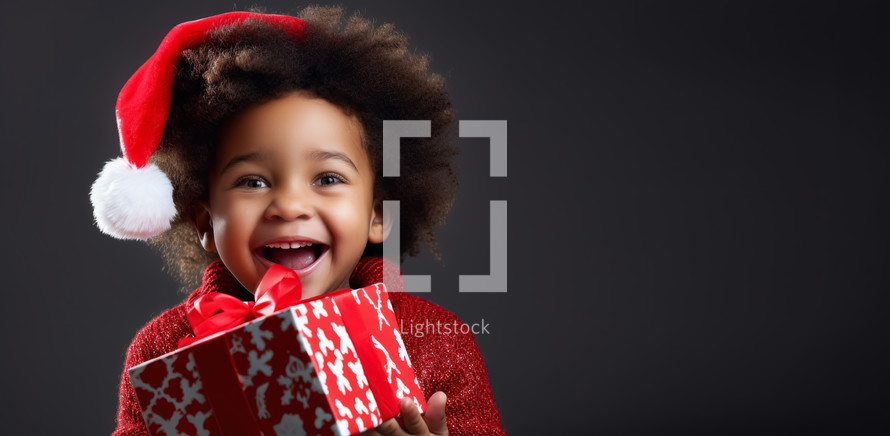 Small cute afro american child with christmas hat holding a present gift. Christmas holiday concept.