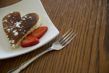 heart shaped pancake on a plate with strawberries 