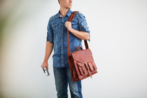 a man standing holding a messenger bag 