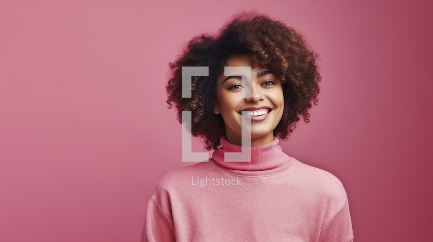 Portrait of a joyful young woman with curly hair wearing a turtleneck sweater, with a pleasant smile against a pink background.