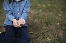 a child kneeling with cupped hands 