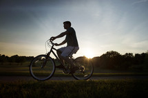 man riding a bicycle at sunset 