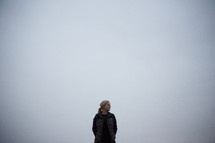A woman standing beneath a cloudy sky.