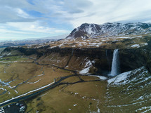 aerial view over a waterfall and snow capped mountain 