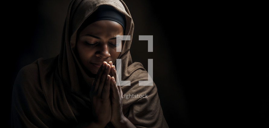 Christian woman in contemplative prayer with hands clasped and eyes closed, serene expression.