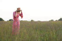 a woman in a pink dress walking through a field 