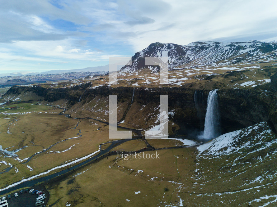 aerial view over a waterfall and snow capped mountain 