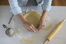 Hands preparing a pie crust for baking.