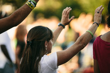 hands raised at an outdoor worship service 