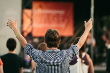 man with his hands raised in worship at an outdoor concert