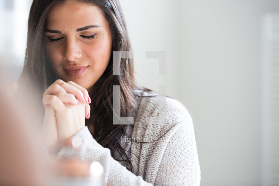 a young woman with praying hands.