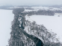 aerial view over a river and snow covered landscape 