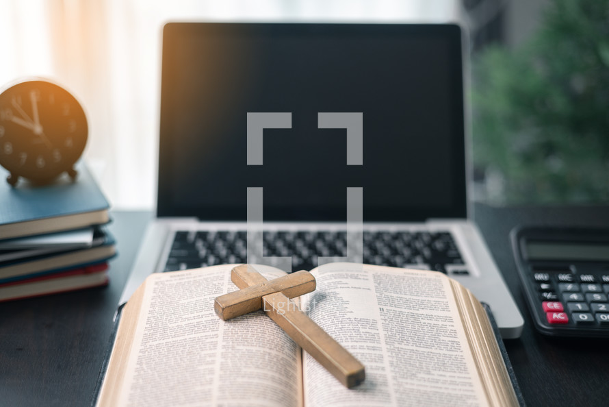 Cross on bible and laptop in online study bible concept. Holy Bible concept for modern religious education, podcast or help with hearing for blind studying