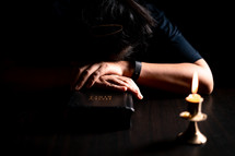 Bible and candlelight with praying woman