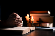 Bible and candlelight with praying hands