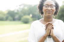 African-American woman with praying hands outdoors 