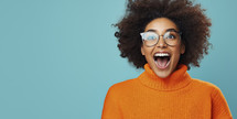 Vibrant portrait of a young woman with curly hair wearing glasses, exuding excitement in an orange turtleneck against a teal background.