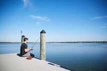 a man sitting on a pier fishing 