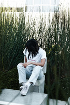 a person sitting outdoors in front of tall grasses 
