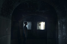 a man standing in a dark cellar alone.
