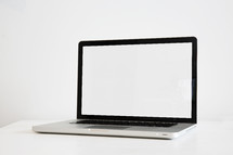 blank laptop computer screen on a white desk.