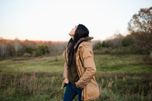 young woman walking looking up outdoors in coat  