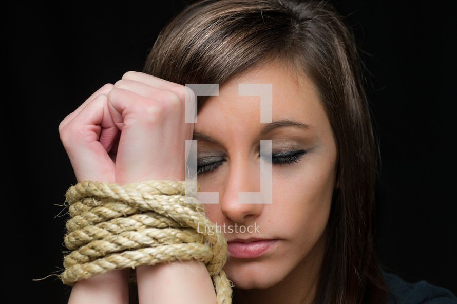Woman with her wrists bound by rope.