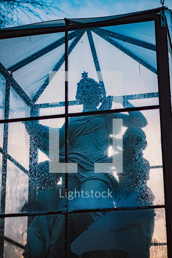 protected statues in a glass enclosure outdoors 