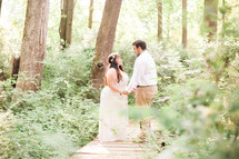 bride and groom holding hands on a wooden path in the woods 