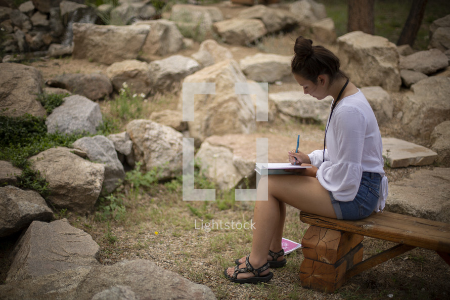 girl sitting outdoors reading her Bible 