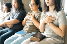 Group praying with hands over their heart