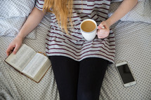 girl sitting on a bed with coffee reading a Bible 