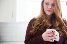 a woman holding a mug of coffee thinking 
