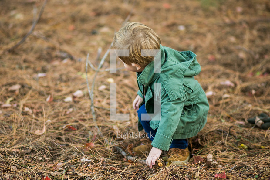 a toddler boy standing outdoors in a jacket 