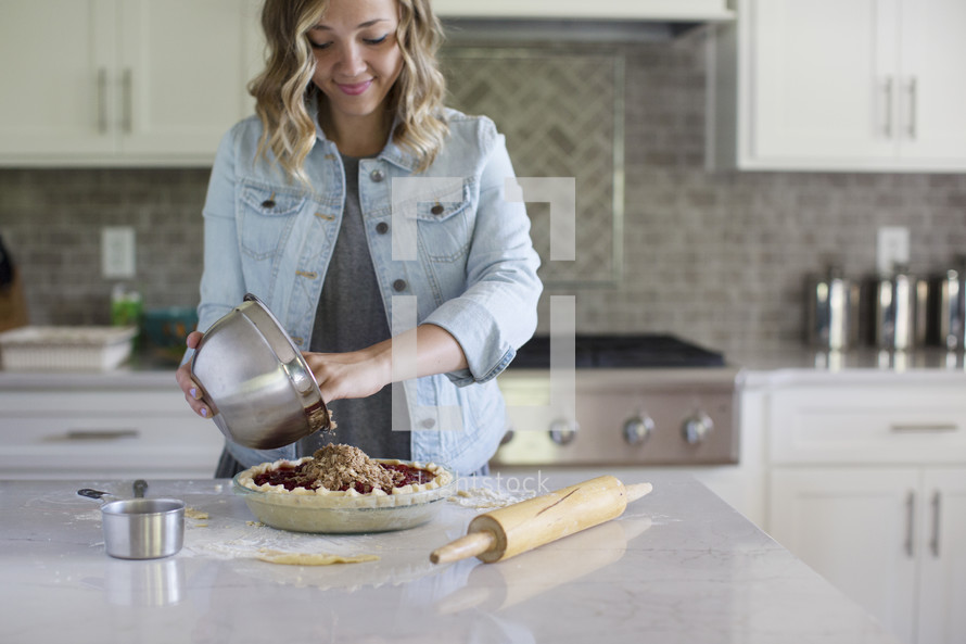 A woman pouring pie filling into a prepared pie crust.