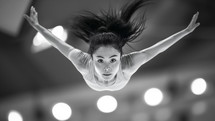 A captivating close-up of a female gymnast in mid-air, demonstrating perfect form and intense focus, under the spotlight at the Olympics.