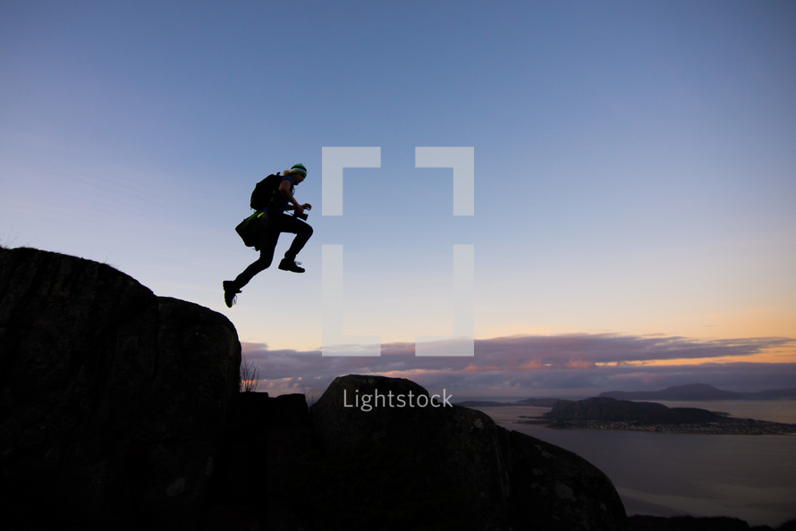 silhouette of a man jumping on a mountainside