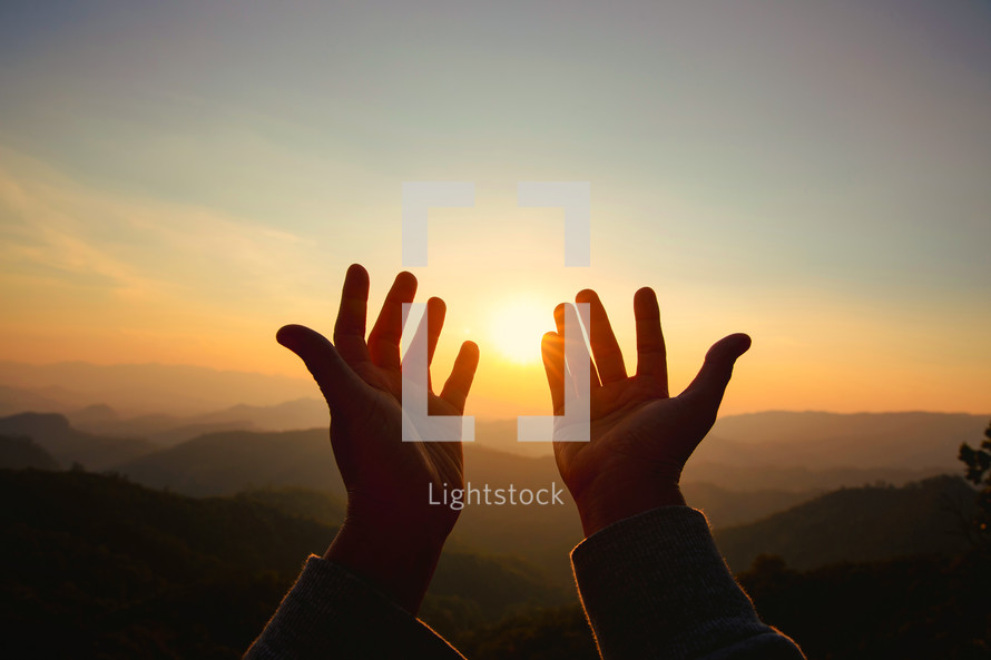 Hands open toward the heavens at sunset