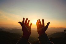 Hands open toward the heavens at sunset