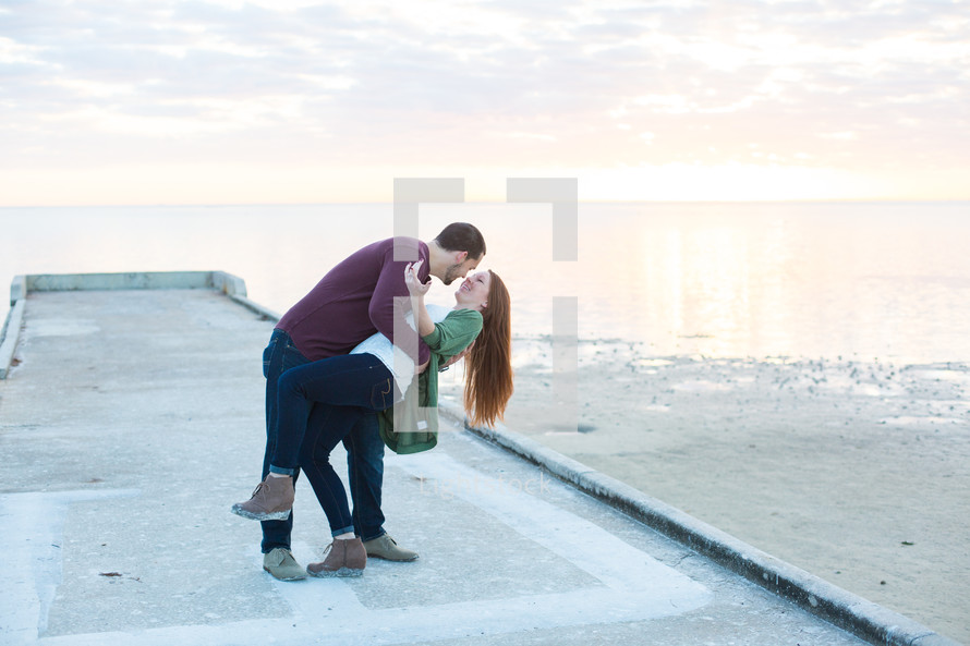 a couple kissing on a beach pier 